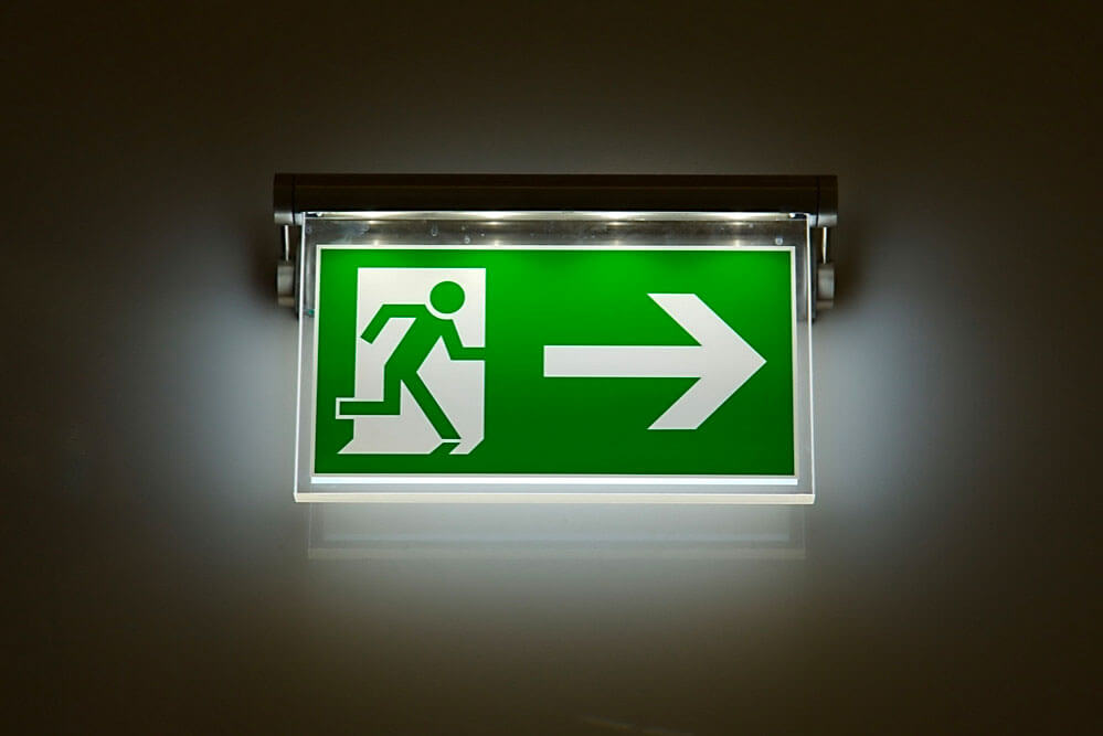Una señal de salida verde con una flecha que apunta en la dirección de una salida.
